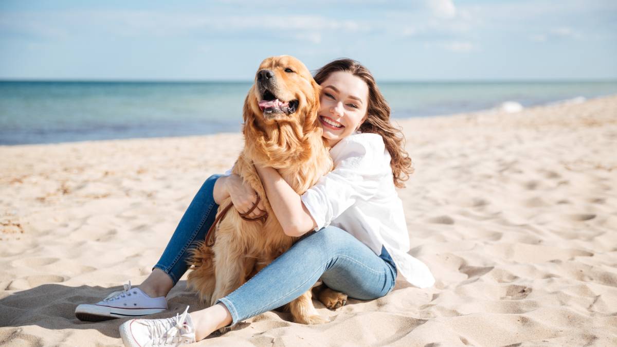 Cane in spiaggia con padrona