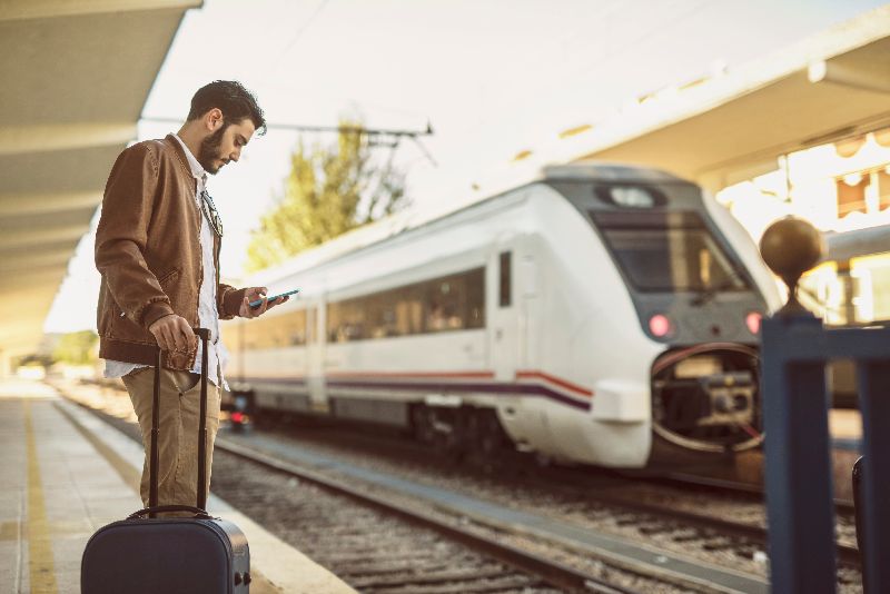 Uomo con cellulare su binario in stazione